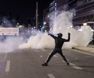 epa10501394 A protester hurls objects towards riot police during a protest over Greece's deadliest train crash, in front of Parliament in Athens, Greece, 03 March 2023. The death toll of the train collision that occurred on the Athens-Thessaloniki line has risen to 57, a Hellenic Police spokesperson confirmed on 02 March 2023. The collision between a passenger train traveling north and a freight train traveling south on the same line occurred on 28 February night.  EPA/GEORGE VITSARAS