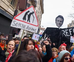 epa10507561 Protesters hold a banner showing French President Macron's face, during a protest against the French government's planned reform of the pension system, in Paris, France, 07 March 2023. The French government plans to delay the minimum retirement age from 62 to 64, until 2030.  EPA/MOHAMMED BADRA