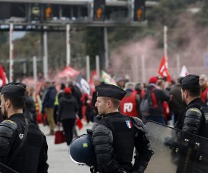 epa10511166 Riot police stand as people block the A9 motorway towards Spain during a new day of protests against the French government's planned reform of the pension system, in Le Boulou, southern France, 09 March 2023. Workers' Force (FO) and General Confederation of Labour (CGT) union members blocked traffic. Protests continue across the country due to the French government's plan to delay the minimum retirement age from 62 to 64 by 2030.  EPA/GUILLAUME HORCAJUELO