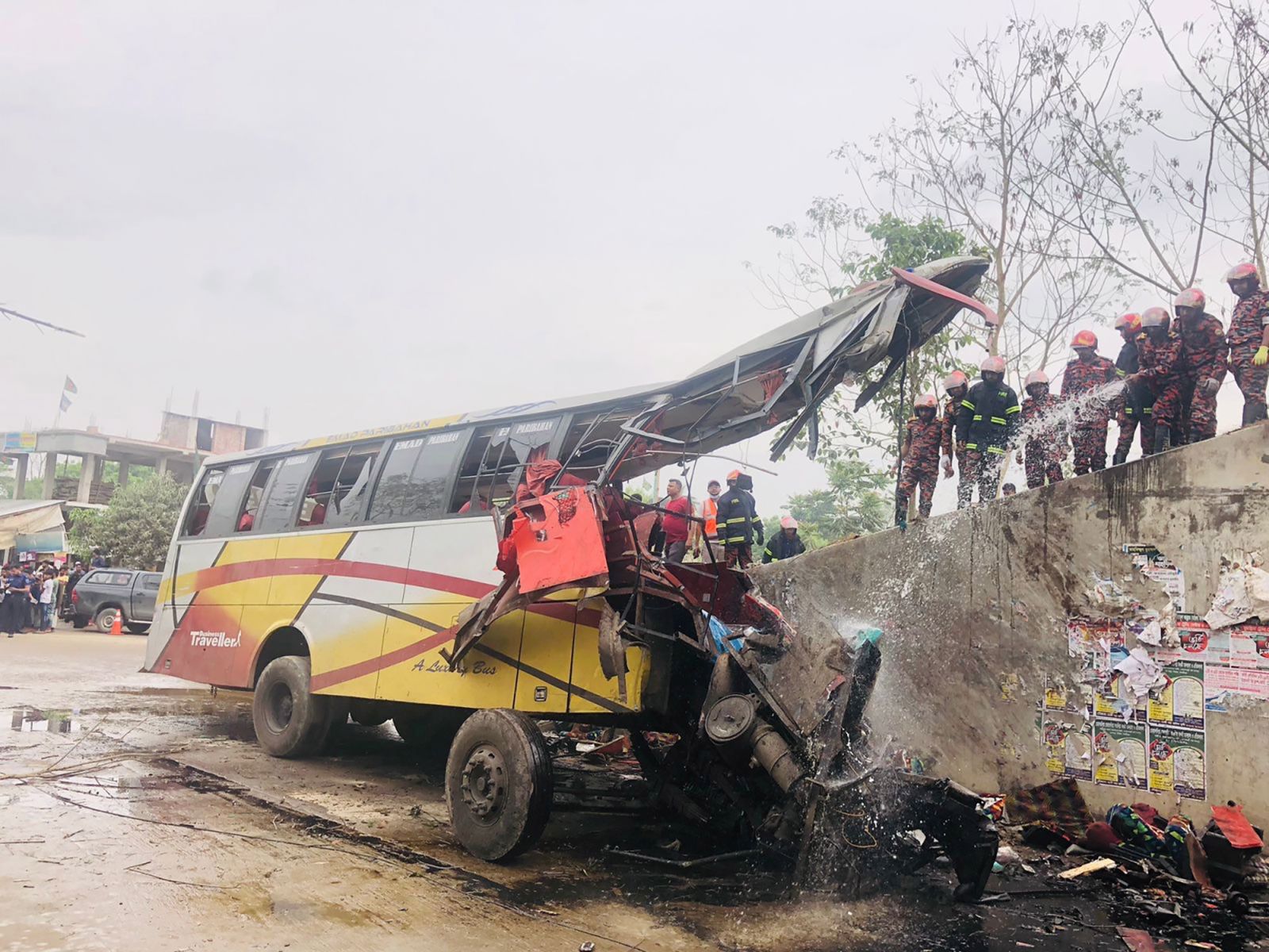 epa10531444 Firefighters hose a fire that after a road accident at Sibchar upazila in the Madaripur district in Bangladesh, 19 March 2023. At least 19 people died and many others were injured according to the firefighters in Madaripur. Police in Madaripur suspects that either a burst wheel or speeding could be the reason behind the accident.  EPA/AJOY KINDU BEST QUALITY AVAILABLE