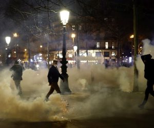 epa10535676 Tear gas floats in the air as protesters clash with French riot police at Republique square during a demonstration against the government pension reform in Paris, France, 21 March 2023. Protests continued in France after the French prime minister announced on 16 March 2023 the use of Article 49 paragraph 3 (49.3) of the French Constitution to have the text on the controversial pension reform law be definitively adopted without a vote in the National Assembly (lower house of parliament). The bill would raise the retirement age in France from 62 to 64 by 2030.  EPA/YOAN VALAT