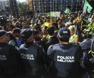 epa10550492 Members of the Military Police watch supporters of former Brazilian president Bolsonaro gather outside the Liberal Party's headquarters in Brasilia, Brazil, 30 March 2023. Bolsonaro returned to Brazil after an 89 days in Florida, USA, to where he traveled two days before his term ended.  EPA/Luis Nova