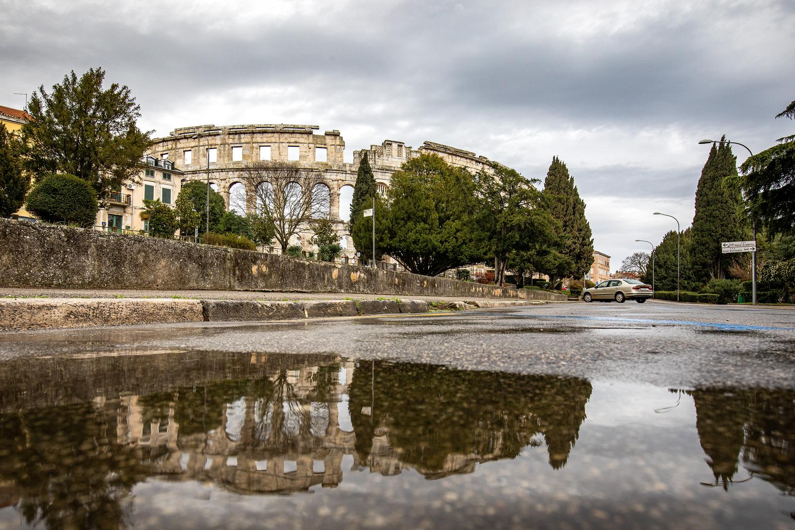 14.03.2023., Pula - Refleksije Arene u lokvicama nakon kise. Photo: Srecko Niketic/PIXSELL