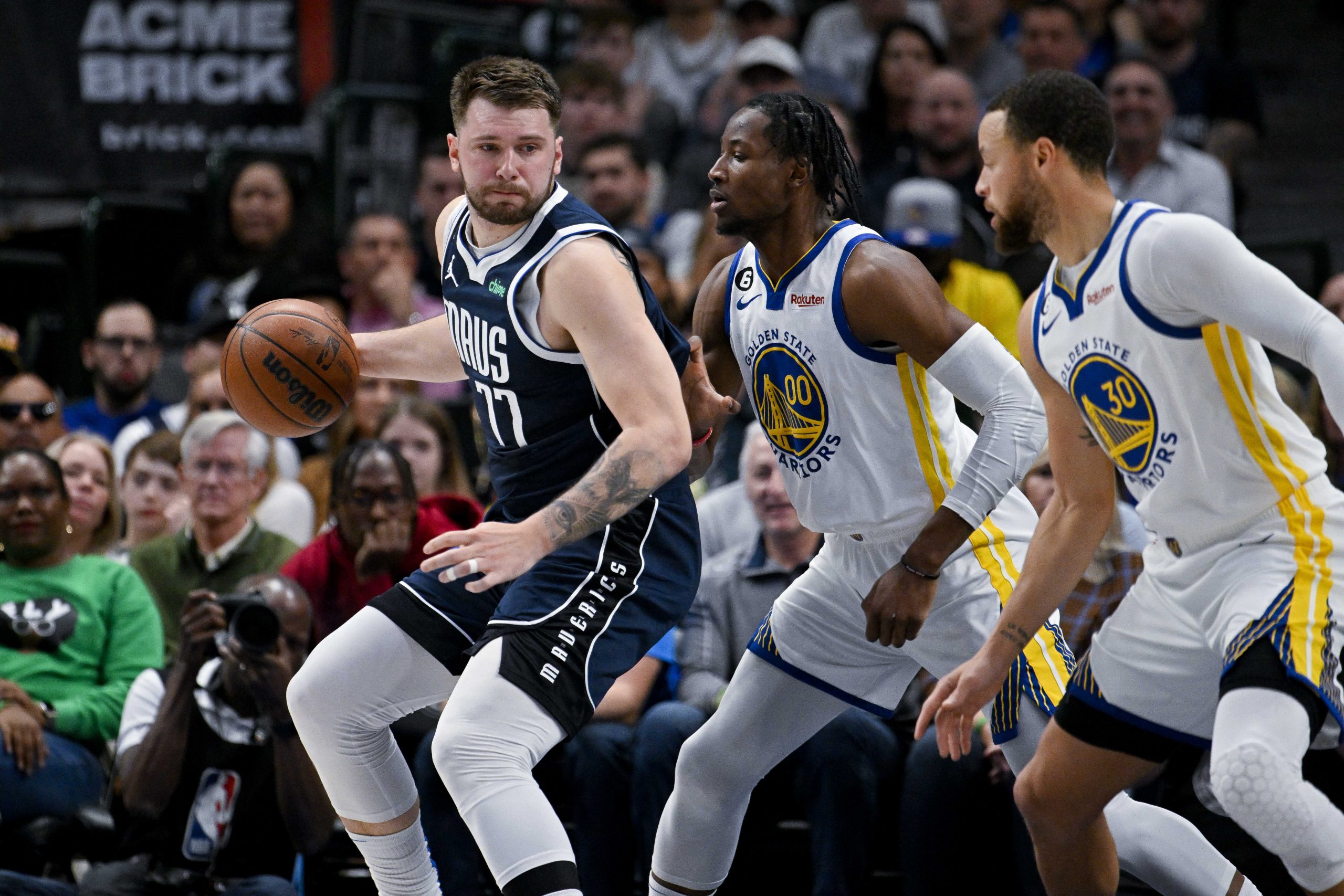 Mar 22, 2023; Dallas, Texas, USA; Dallas Mavericks guard Luka Doncic (77) looks to move the ball past Golden State Warriors forward Jonathan Kuminga (00) and guard Stephen Curry (30) during the first quarter at the American Airlines Center. Mandatory Credit: Jerome Miron-USA TODAY Sports Photo: Jerome Miron/REUTERS