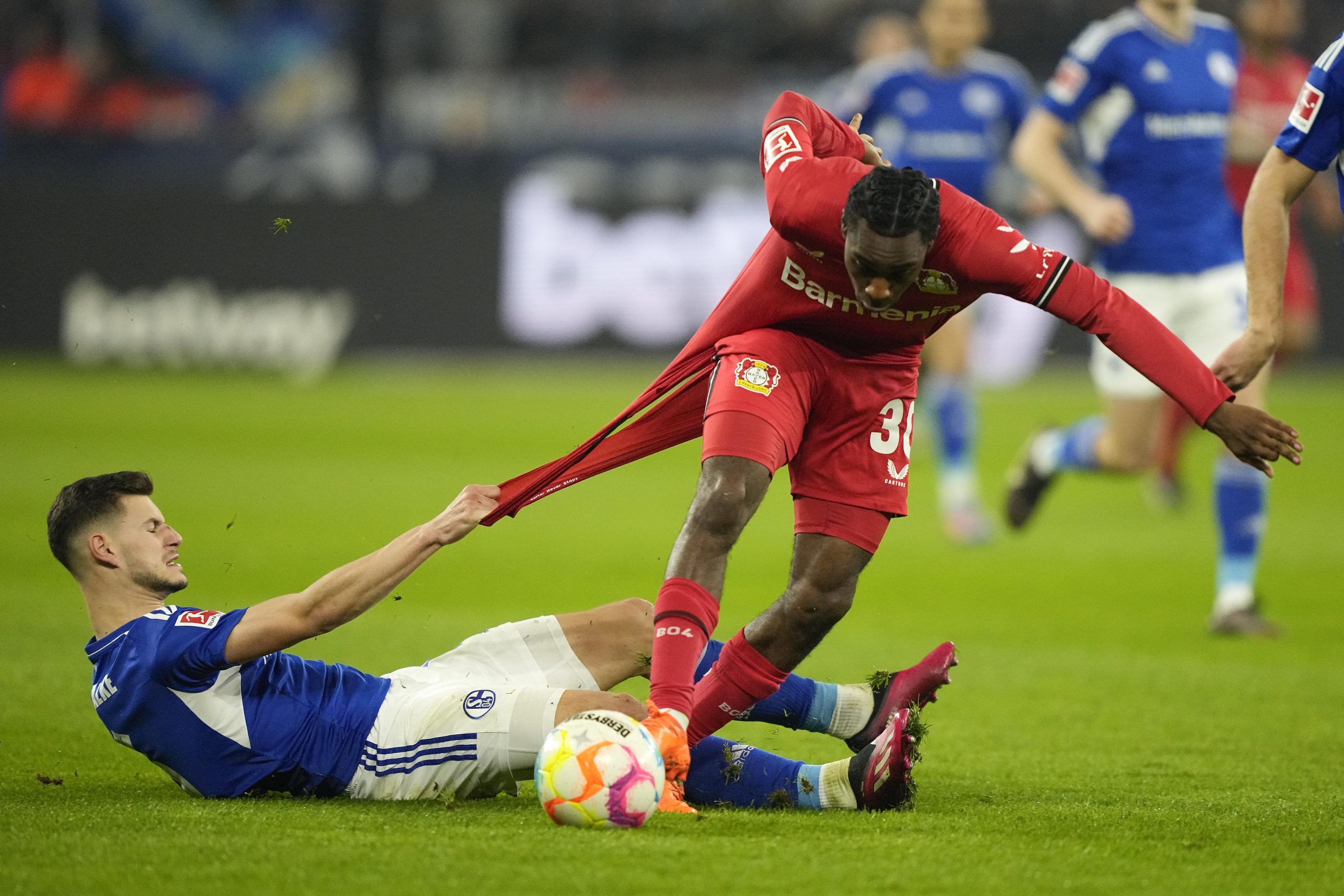 Schalke's Tom Krauss, left, and Leverkusen's Jeremie Frimpong challenge for the ball during the German Bundesliga soccer match between Schalke 04 and Bayer Leverkusen in Gelsenkirchen, Germany, Saturday, April 1, 2023. (AP Photo/Martin Meissner)