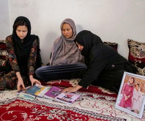 epa10539927 Mothers of deceased cousins Marzia, 18, and Hajar, 19, and Marzia's elder sister Zahra Mohammadi (L) arrange their books next to a picture of them at their home in Kabul, Afghanistan, 22 March 2023 (issued 24 March 2023). The two cousins were killed among tens of other students, mostly female, who had gathered for a practice university entrance exam at an institute of Kabul in September 2022, following a suicide bomb attack. In tribute to the girls, their families placed a library with their favorite books on their grave at a graveyard in Dasht-e-barchi area.  EPA/SAMIULLAH POPAL