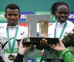 epa10555078 Ethiopian runner Abeje Ayana (L) and Kenyan runner Helah Kiprop (R) celebrate their win on the podium following the 46th edition of the 'Schneider Electric Marathon de Paris 2023’ in Paris, France, 02 April 2023.  EPA/YOAN VALAT