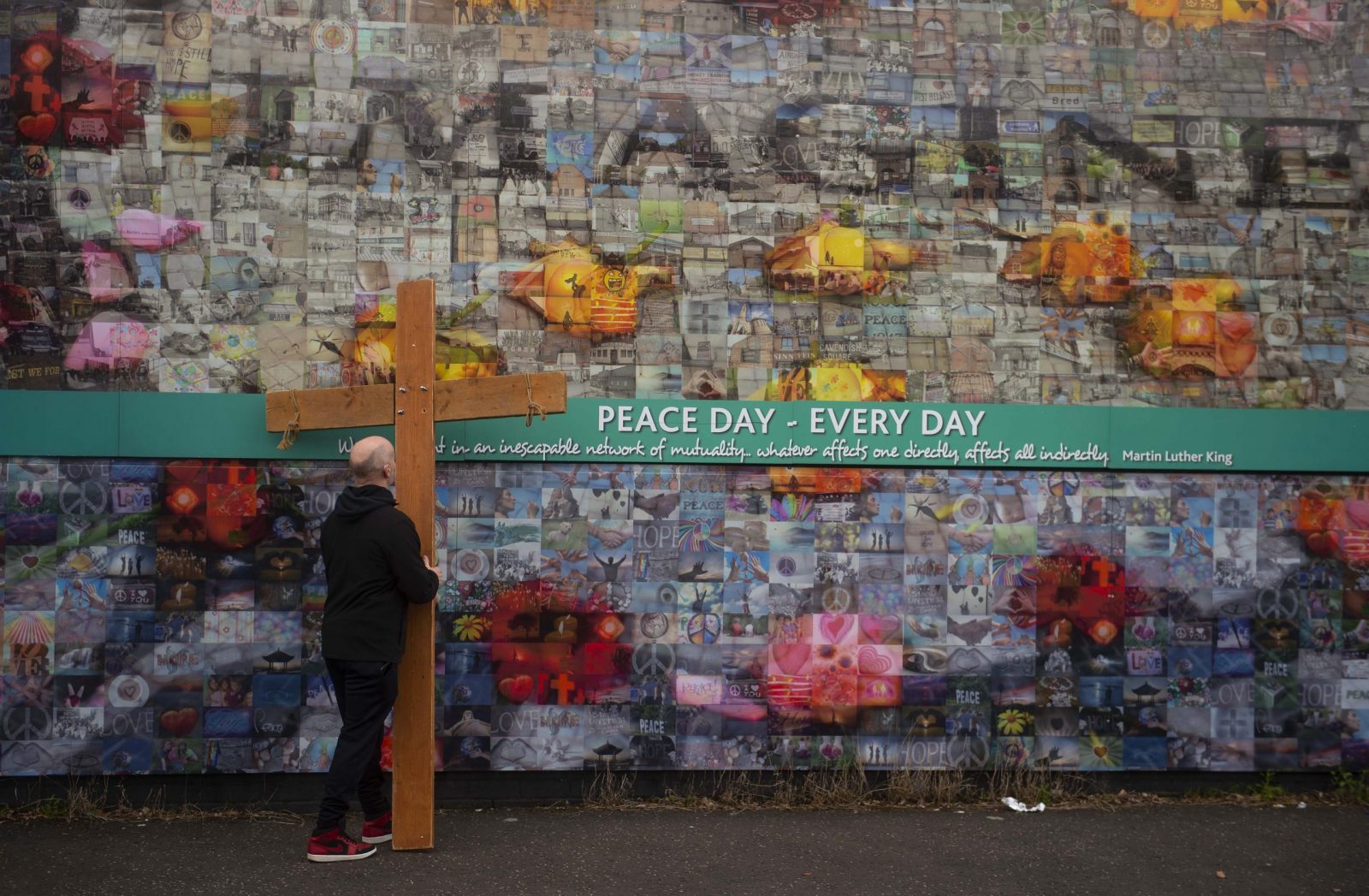 epa10563272 A man walks with a cross as residents from the Falls and Shankill Roads create a Human Peacewall at Northumberland Street to form a line of solidarity between the two communities to mark the 25th anniversary of the Northern Ireland Agreement in Belfast, Northern Ireland, Britain, 7 April 2023. The Good Friday Agreement was signed on 10 April 1998. The agreement ended the violent phase of the political conflict in Northern Ireland and is seen as the major development in the Northern Ireland peace process of the 1990s.  EPA/MARK MARLOW