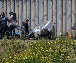 epa10569719 Migrants gather in a makeshift camp next to the border wall in Tijuana, Baja California, Mexico, 11 April 2023 (issued 12 April 2023). More than 150 migrants, including children, have been camping for more than seven days between the walls of Mexico's northern border with the USA, seeking asylum in the United States, a fact that reflects the growing crisis three months after the new US restrictions.  EPA/Joebeth Terriquez