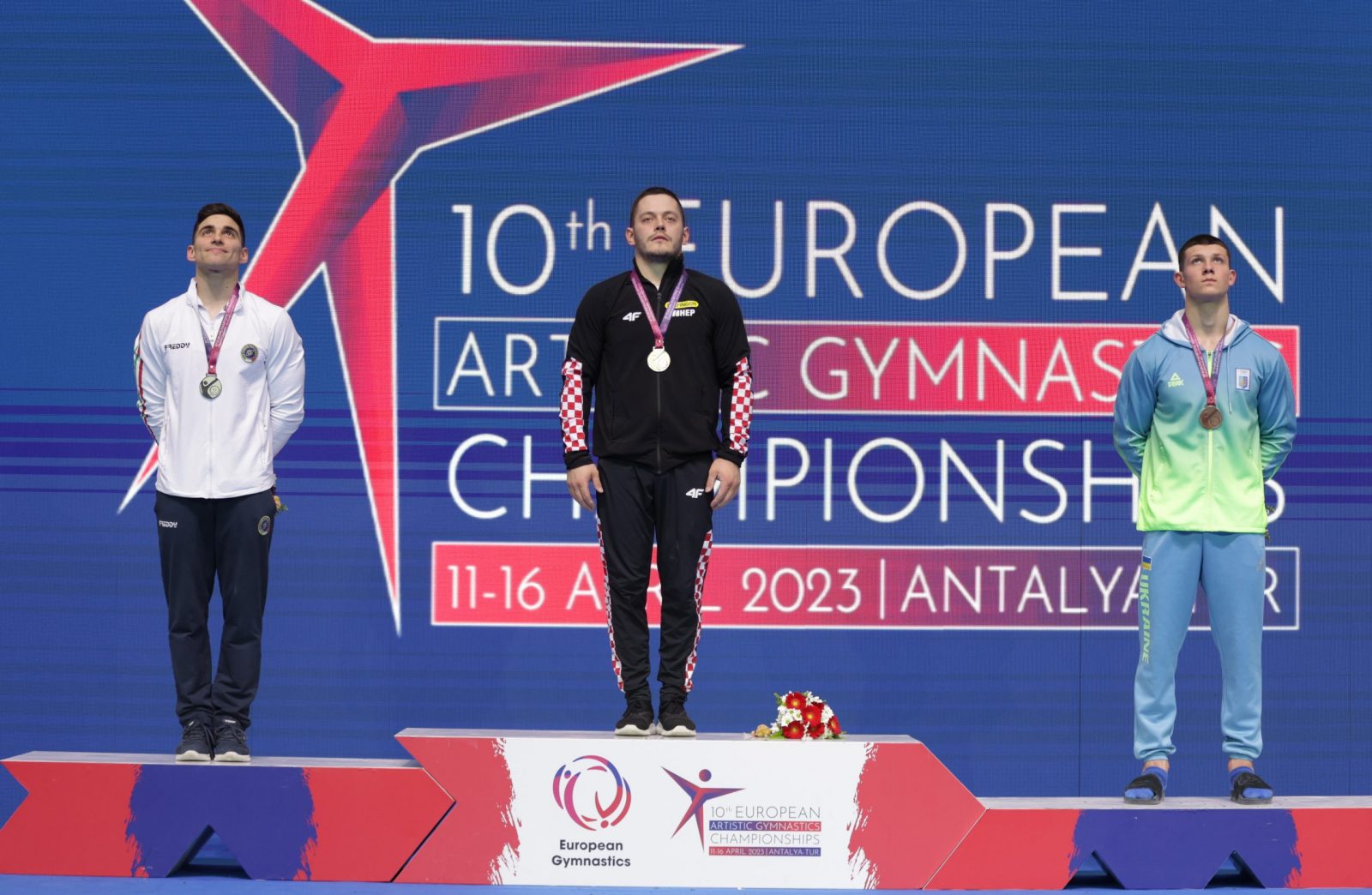 epa10575701 Gold medalist Tin Srbic (C) of Croatia, Silver medalist Carlo Macchini (L) of Italy and Bronze medalist Illia Kovtun (R) of Ukraine pose during the award ceremony for the Men's Horizontal Bar of the Artistic Gymnastics European Championships in Antalya, Turkey, 16 April 2023.  EPA/ERDEM SAHIN