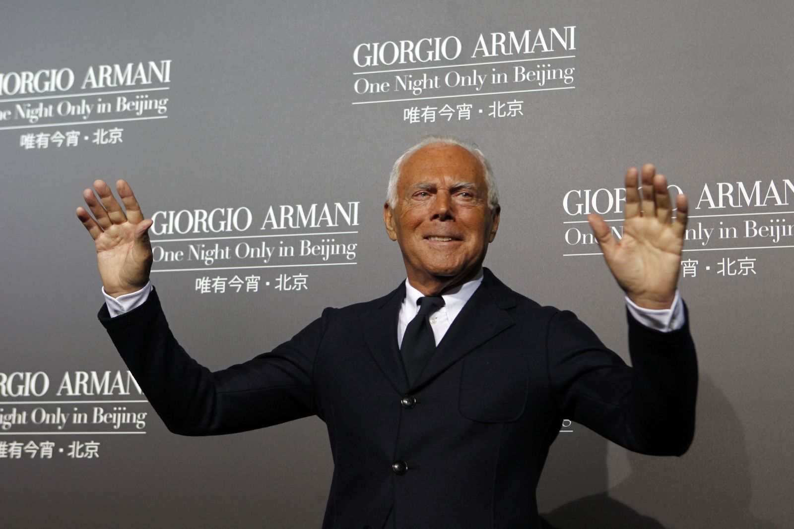 Designer Giorgio Armani gestures as he greets photographers before the start of his fashion show in Beijing, China, Thursday, May 31, 2012. (AP Photo/Ng Han Guan)
