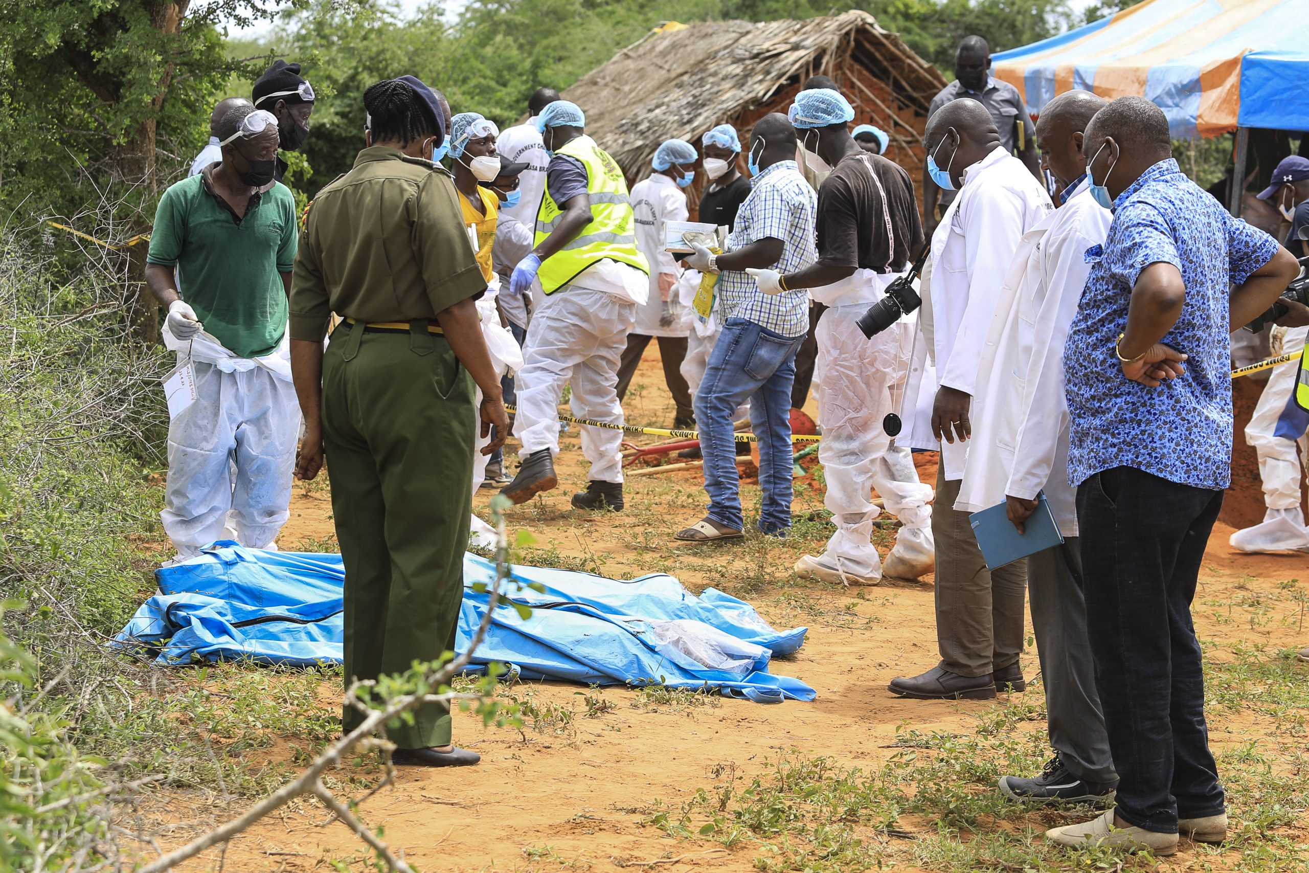 epa10588064 Kenyan homicide detectives and forensic experts from the Directorate of Criminal Investigations (DCI), examine exhumed bodies from several shallow mass graves of suspected members of a Christian cult after starving themselves to death, after allegedly being told by their controversial preacher Paul Mackenzie that they would go to heaven if they starved themselves to death, in the coastal Shakahola forest, in Kilifi, Kenya, 23 April 2023. According to the Police, 18 more bodies were exhumed on 23 April bringing the tally of bodies recovered to at 39.  EPA/STR