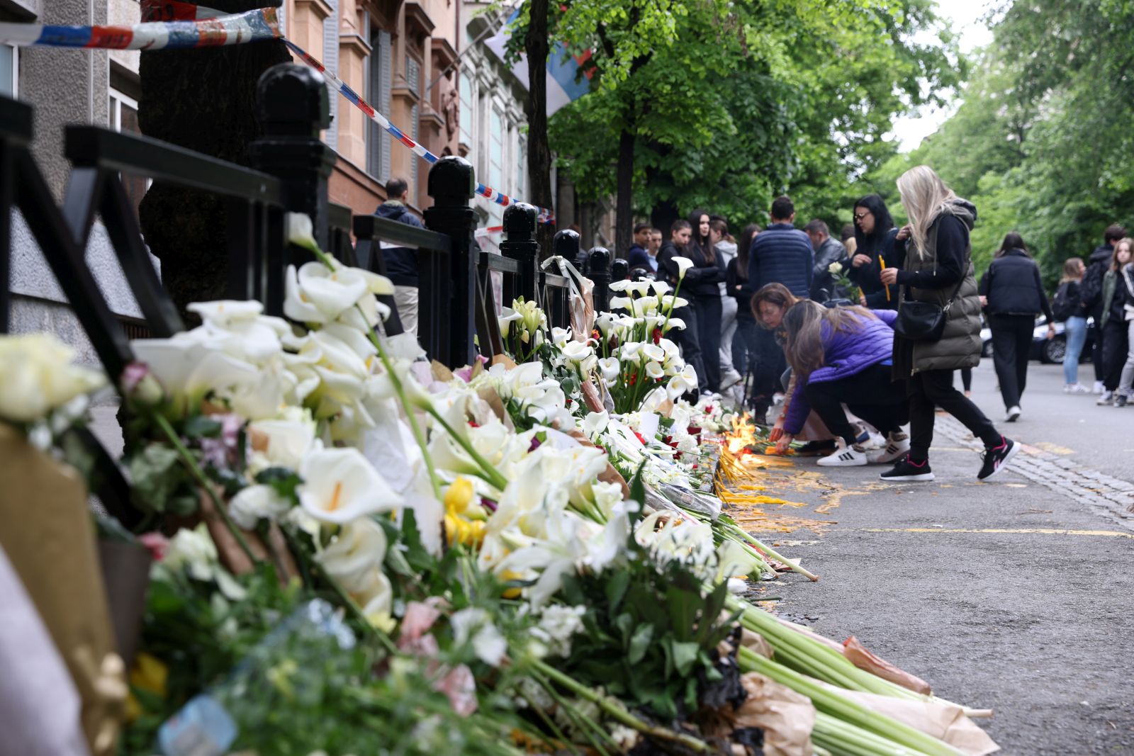 epa10607861 People leave flowers and light candles for the victims in front of the "Vladislav Ribnikar" elementary school in Belgrade, Serbia, 04 May 2023. A teenage student fatally shot seven girls and one boy using two handguns, which he had taken from his father. Six children and a teacher were also injured in the attack.  EPA/ANDREJ CUKIC