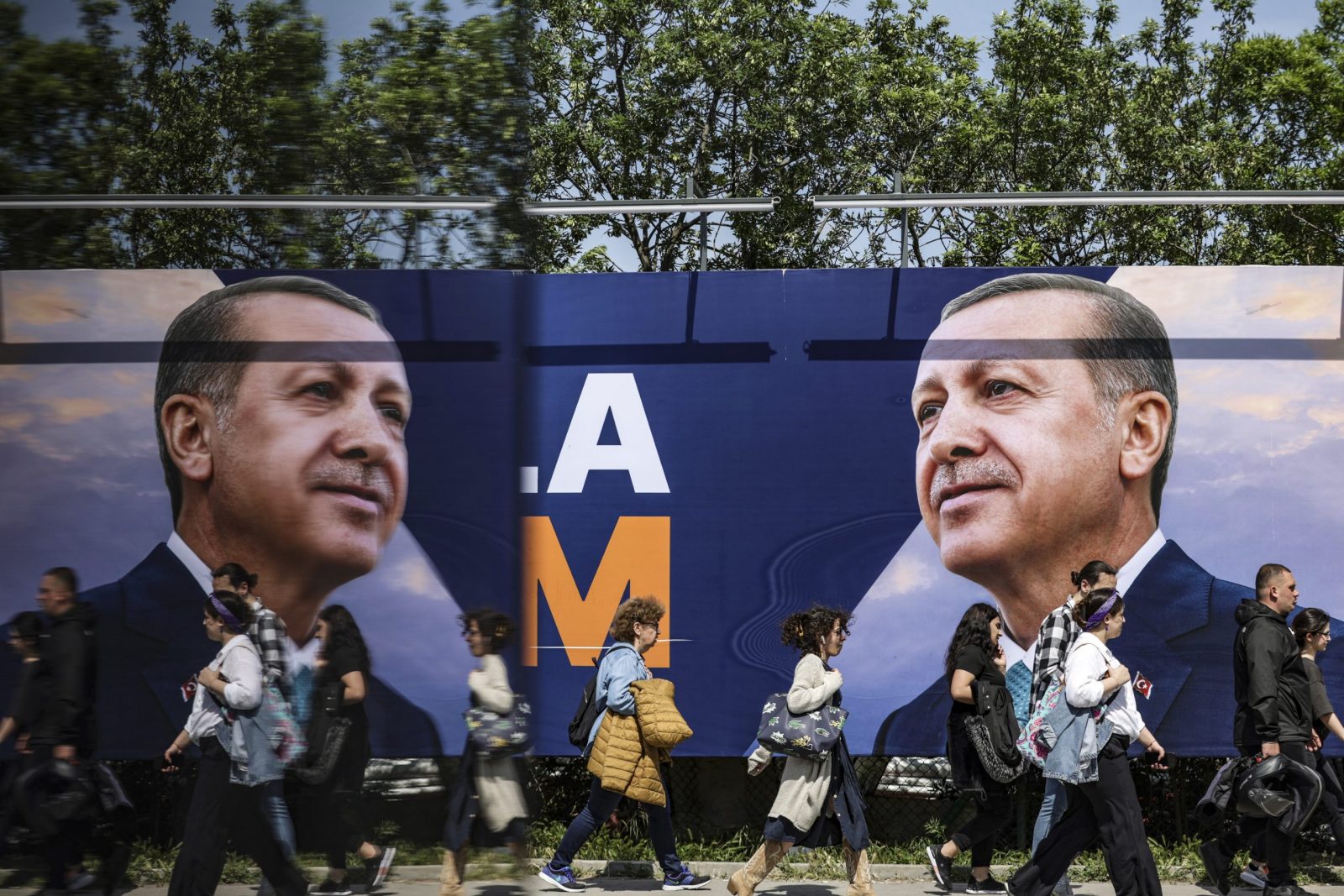 epa10646259 People walk in front of an election campaign poster of Turkish President Recep Tayyip Erdogan, in Istanbul, Turkey, 22 May 2023. General elections had been held in Turkey on 14 May, where none of the candidates exceeded the 50 percent mark in the first round. The second round of presidential elections between Turkish President Recep Tayyip Erdogan and his challenger Kemal Kilicdaroglu, the leader of the opposition Republican People's Party (CHP), will be held on 28 May.  EPA/ERDEM SAHIN