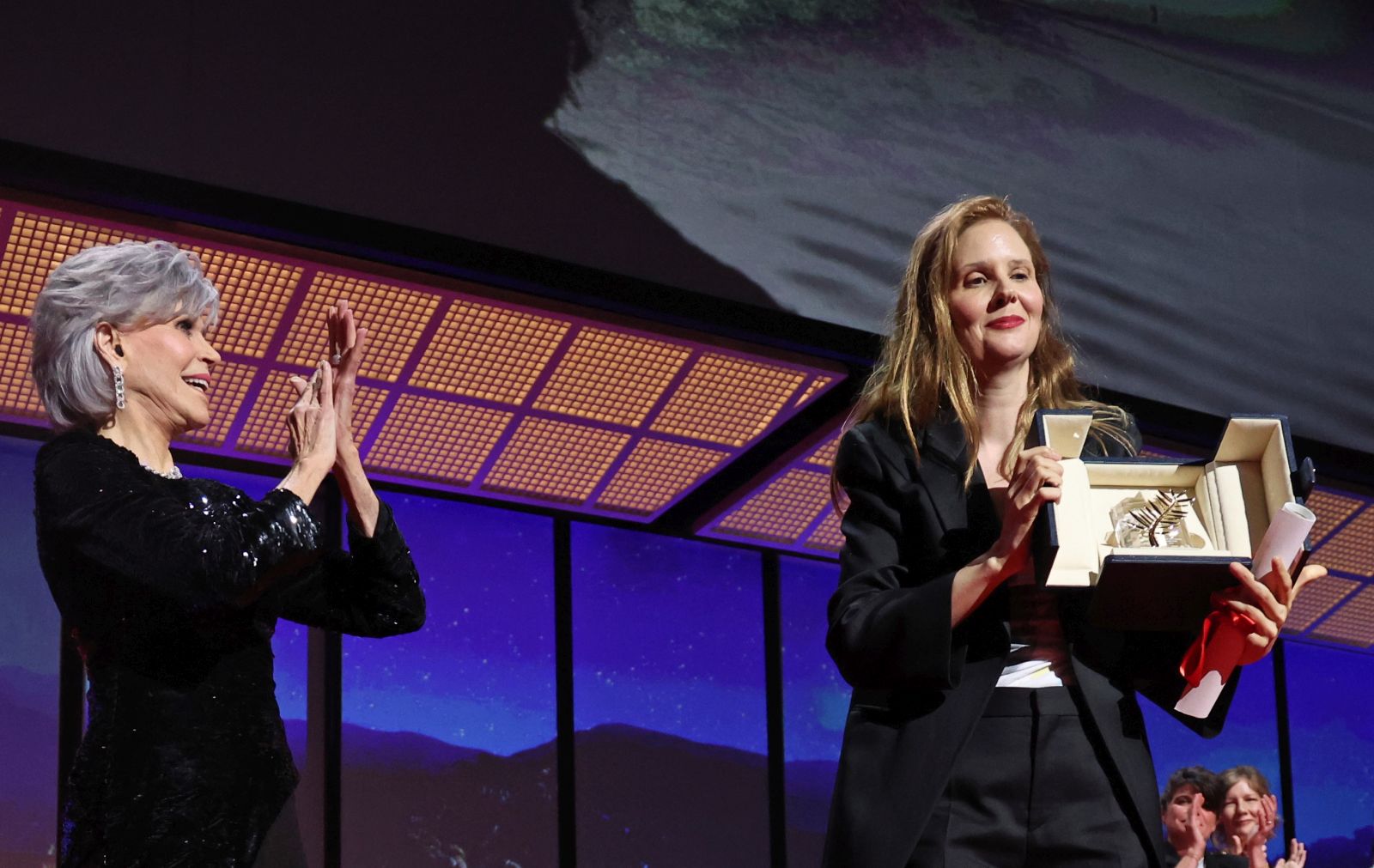 epa10658717 Justine Triet (C) is applauded by US acrtress Jane Fonda (L) as she holds the Palme D'Or Award for her movie 'Anatomy of a Fall' during the Closing Ceremony of the 76th annual Cannes Film Festival, in Cannes, France, 27 May 2023.  EPA/MOHAMMED BADRA