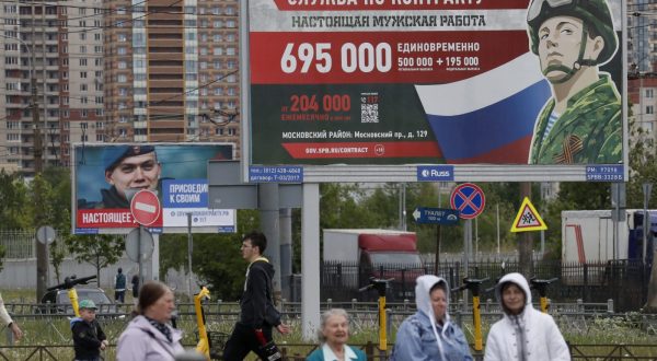 epa10662045 People walk past a billboard depicting a soldier, with a slogan reading 'Contract service. A real man's job' and 'Real deal. Join with your comrades', in St. Petersburg, Russia, 29 May 2023. On 24 February 2022, Russian troops entered Ukrainian territory in what the Russian president declared a 'Special Military Operation', starting an armed conflict.  EPA/ANATOLY MALTSEV