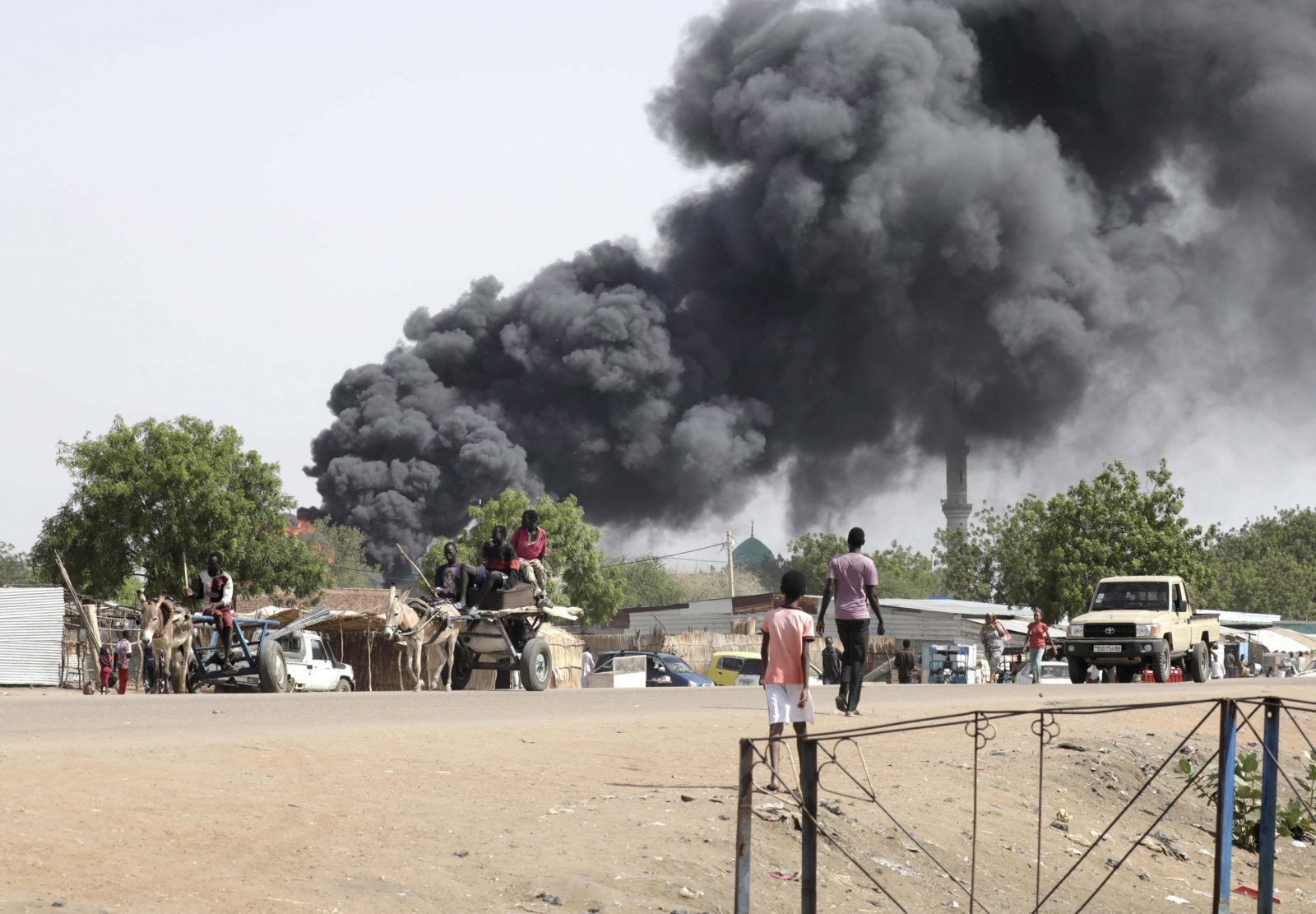 epa10625669 People drive as smoke rises from a fire at a market in the Upper Nile State town of Renk, South Sudan, 13 May 2023. According to UNHCR, at least 40,000 people have arrived into South Sudan since armed clashes between Sudan's military and rival paramilitary groups began in Khartoum and other parts of the country on 15 April 2023. Most of the refugees are part of the some 800,000 South Sudanese who had previously fled the war in South Sudan and who are now returning to a country with tensions still remaining in many areas, and more than two million internally displaced people. Upon arriving at the Joda border crossing, the refugees head to a transit area set up by UNHCR in the small town of Renk, where various UN agencies assist them with registration, food, health check and logistics.  EPA/AMEL PAIN