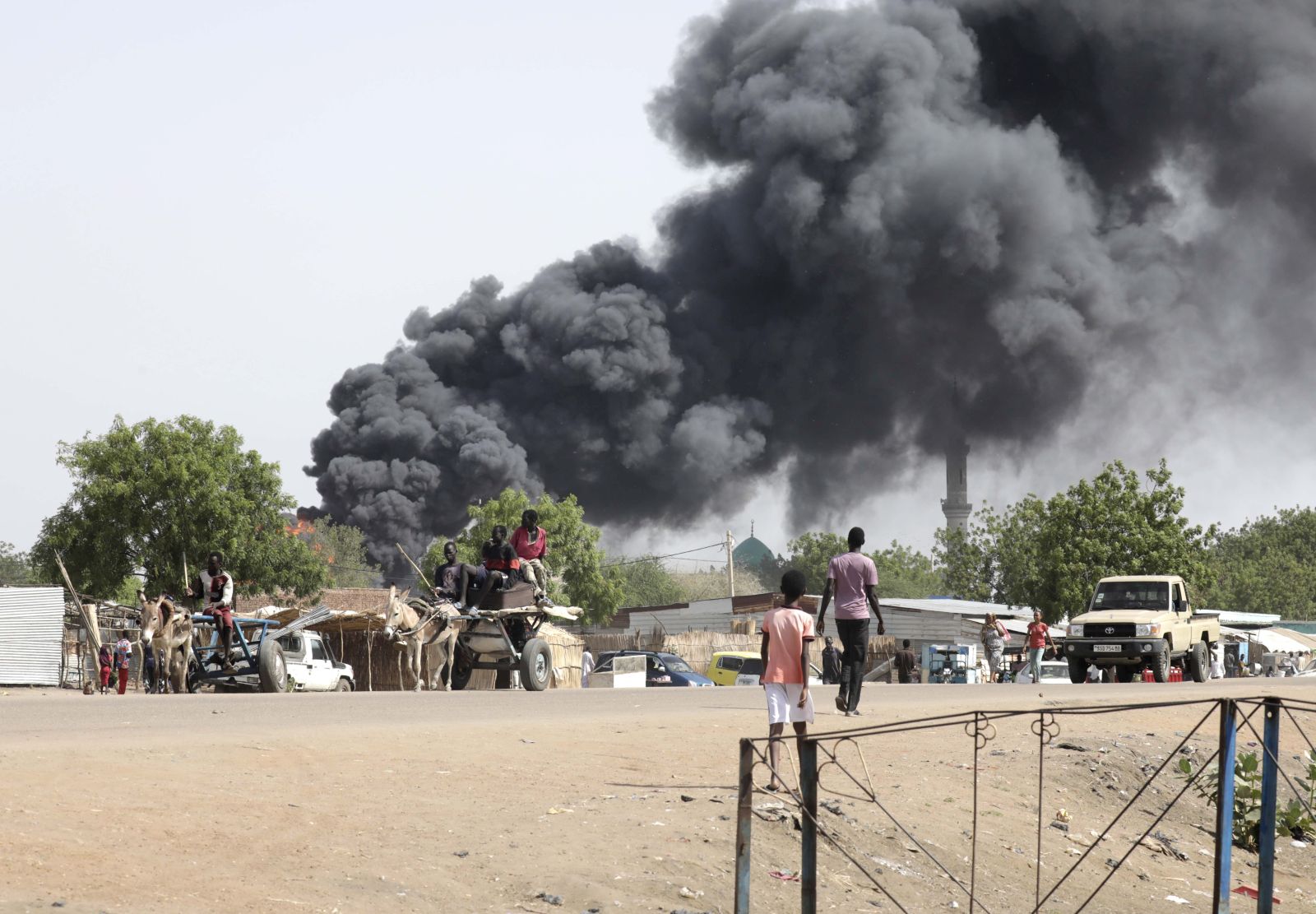 epa10625669 People drive as smoke rises from a fire at a market in the Upper Nile State town of Renk, South Sudan, 13 May 2023. According to UNHCR, at least 40,000 people have arrived into South Sudan since armed clashes between Sudan's military and rival paramilitary groups began in Khartoum and other parts of the country on 15 April 2023. Most of the refugees are part of the some 800,000 South Sudanese who had previously fled the war in South Sudan and who are now returning to a country with tensions still remaining in many areas, and more than two million internally displaced people. Upon arriving at the Joda border crossing, the refugees head to a transit area set up by UNHCR in the small town of Renk, where various UN agencies assist them with registration, food, health check and logistics.  EPA/AMEL PAIN