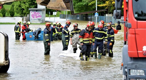 Karlovac, 17.05.2023. - U utorak postavljeni zečji nasipi na desnoj obali Korane uz SRC "Korana" i Aquatiku - slatkovodni akvarij nisu izdržali nalet Korane, pa su u pomoć u obrani Aquatike od poplavljivanja karlovačkim vatrogascima stigli kolege iz Zagreba, Sesveta, Daruvara, Bjelovara, Hrašća, Grubišnog Polja i mnogo drugih mjesta. Mehanizaciju je za tu akciju dala Hrvatska vojska, a vatrogasce i vreće s pijeskom moralo se do Aquatike prevesti čamcima HGSS-a, kao vatrogasnim kamionima. 
foto HINA/ Mladen VOLARIĆ/ ml