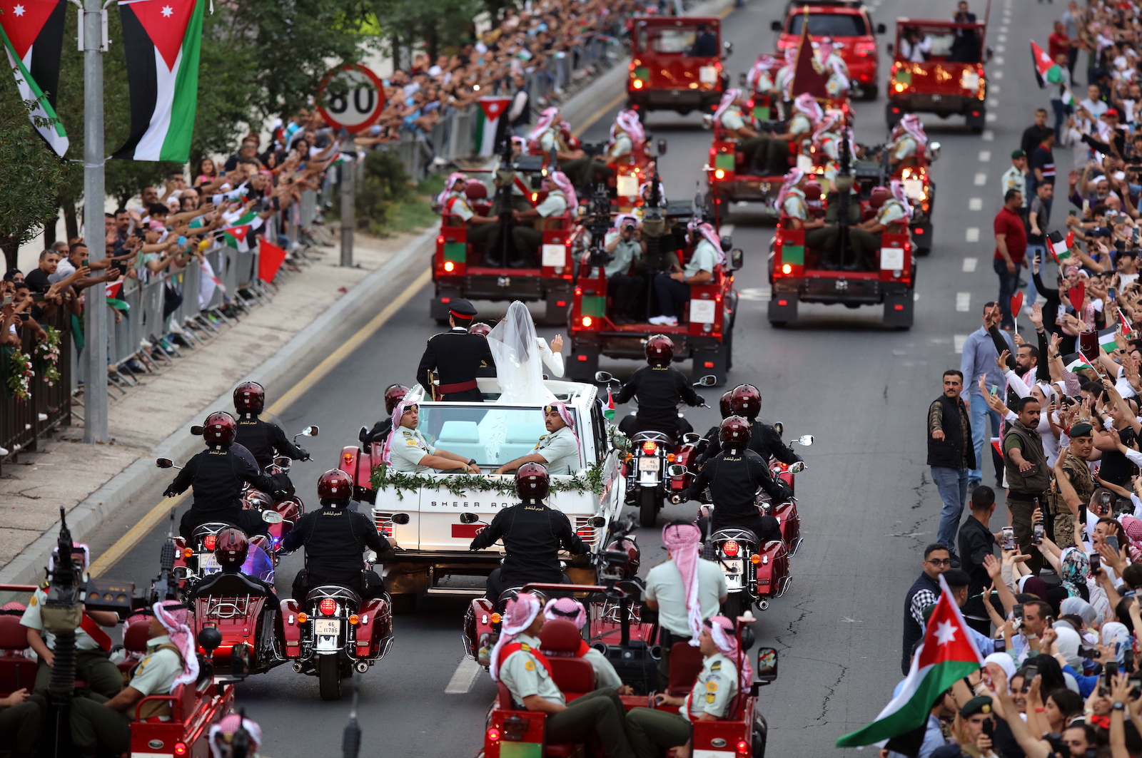 epa10667306 Jordanian Crown Prince Hussein (C-L) and his wife, Princess Rajwa Al Saif (C-R), of Saudi Arabia, wave to people lining the street during a wedding parade after their royal wedding ceremony in Amman, Jordan 01 June 2023. The wedding was held at Zahran Palace attended by Jordan's king and queen, the parents of the bride, and international royals and heads of state.  EPA/MOHAMMAD ALI