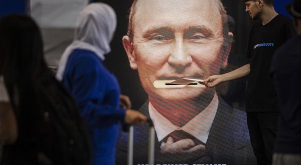 epa10675710 A man throws a voting envelope into a letter box on a screen promoting the climate law referendum showing a portrait of Russian President Vladimir Putin and the writing 'Upset Putin with your voice' ahead of a popular vote scheduled for June 18, 2023, at Zurich main station in Zurich, Switzerland, 06 June 2023. Switzerland sends Russia several millions Swiss francs for oil and natural gas every day, that means Switzerland is indirectly financing the war in Ukraine, the myclimate foundation claims in a statement.  EPA/MICHAEL BUHOLZER