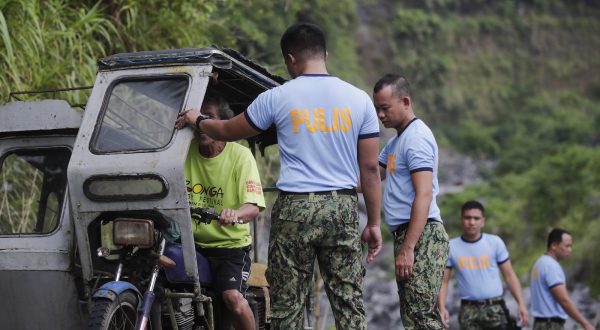 epa10689932 Police officers check a motorist along a street near Mayon volcano's danger zone in the town of Malilipot, Albay province, Philippines, 14 June 2023. Students are forced to attend classes outside of the classrooms, after their school turned into an evacuation center, in Malilipot township, overwhelmed with fleeing villagers from the Mayon volcano's danger area. The Mayon volcano began spewing lava and sulfuric gas on 11 June, prompting the evacuation of thousands of residents.  EPA/FRANCIS R. MALASIG