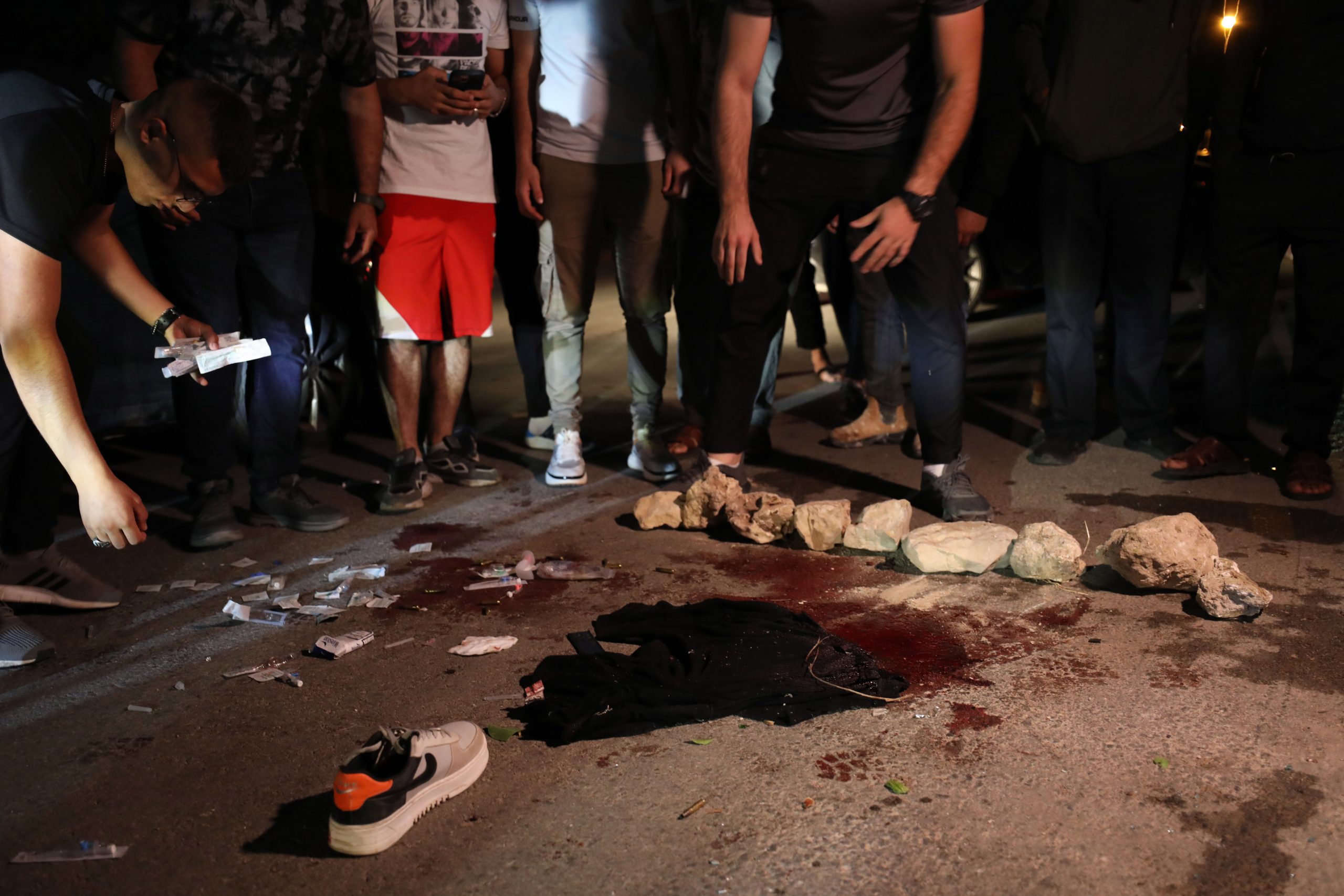 epa10700645 People gather around a blood stain at the scene where two Palestinians were wounded after Israeli soldiers fired at their car near the village of Yabad, near the West Bank city of Jenin, 19 June 2023. The Palestinian Ministry of Health confirmed that two Palestinians were wounded, one of them seriously. The incident comes after at least five people were killed earlier in the day during an Israeli army raid in the West Bank city of Jenin.  EPA/ALAA BADARNEH  19420