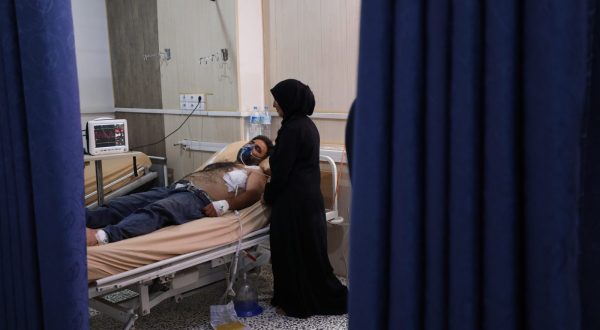 epa10710618 A woman stands next to a man injured in strike on a vegetable market while receiving treatment at a hospital in Idlib, Syria, 25 June 2023. According to the civil defense group operating in the rebel-held Idlib, at least nine people were killed and 30 injured in airstrikes targeting a vegetable and fruit market on the outskirts of Jisr al-Shughour, west of Idlib.  EPA/YAHYA NEMAH
