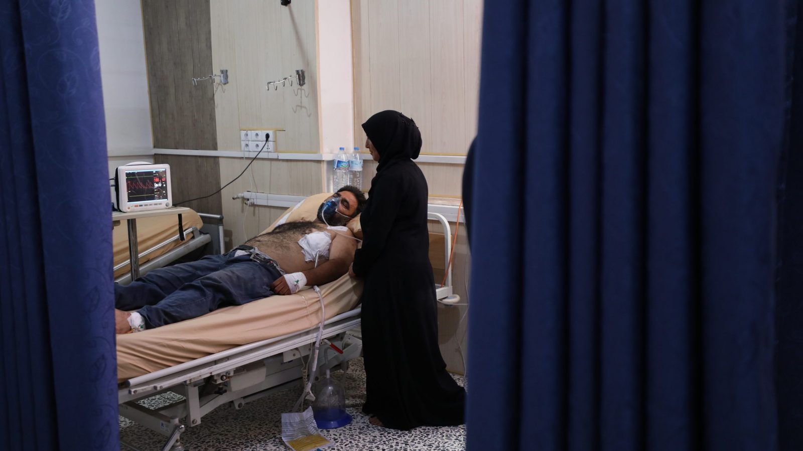 epa10710618 A woman stands next to a man injured in strike on a vegetable market while receiving treatment at a hospital in Idlib, Syria, 25 June 2023. According to the civil defense group operating in the rebel-held Idlib, at least nine people were killed and 30 injured in airstrikes targeting a vegetable and fruit market on the outskirts of Jisr al-Shughour, west of Idlib.  EPA/YAHYA NEMAH