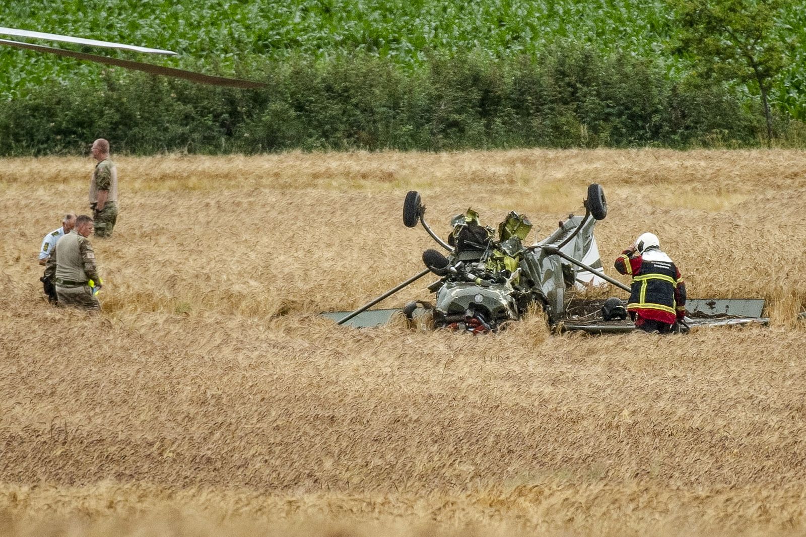 epa10717507 Members of the Danish Army and emergency staff are seen at the scene where a T-17 training aircraft crashed on a field east of Vinderup near Skive, Denmark, 29 June 2023. Two people were injured after Danish Air Forces' training aircraft crashed.  EPA/MORTEN STRICKER  DENMARK OUT