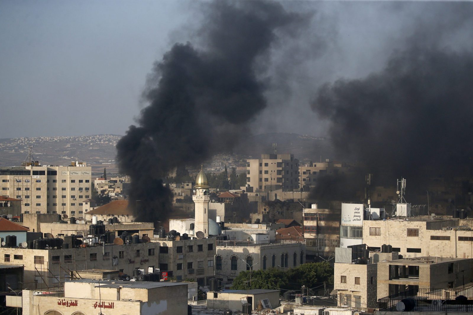 epa10726344 Smoke rises among buildings during clashes with the Israeli army on the second day of a military operation in Jenin camp, West Bank, 04 July 2023. The Israeli army stated on 03 July that they launched a large-scale operation in Jenin. According to the Palestinian Health Ministry, at least ten people were killed and dozens of others wounded in the raid, adding that the death toll was likely to rise.  EPA/ALAA BADARNEH