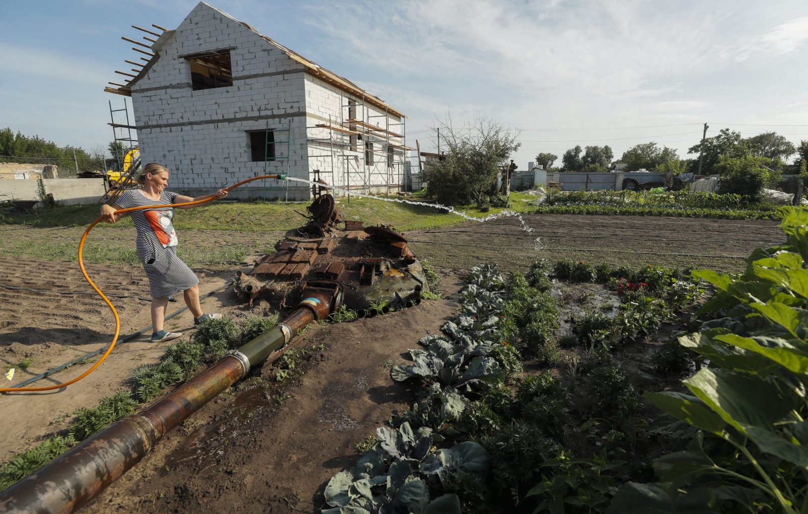 epa10734045 Yulia Semynog waters vegetables next to the remains of a Russian tank in the garden near her home at the village of Velyka Dymerka, Kyiv region, Ukraine, 05 July 2023 (issued 08 July 2023). Valeriy and Yulia Semynog, together with their three children, left their home when Russian troops arrived at Velyka Dymerka in March 2022. The family returned to their village only after Russian troops were pushed out from the Kyiv region in April 2022. They found their home destroyed along with the wreckage of a Russian tank in the garden. The locals planted flowers and vegetables between and around the wreckage of the tank. Velyka Dymerka as well as other towns and villages in the northern part of the Kyiv region, had become battlefields, heavily shelled, causing death and damage when Russian troops tried to reach the Ukrainian capital of Kyiv in February and March 2022.The war in Ukraine, marks on 08 July its 500th day.  According to the UN more than 9000 civilians have been killed since the war started.  EPA/SERGEY DOLZHENKO