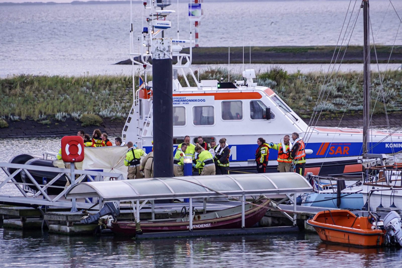 epa10768928 Emergency services bring crew members of the Fremantle Highway cargo ship ashore in Lauwersoog, the Netherlands, 26 July 2023. A fire broke out overnight on 26 July on a freighter with 23 crew members onboard, in the North Sea, north of Ameland. According to the Dutch Coast Guard, one person died, and several got hurt.  EPA/PRESS AGENCY METER