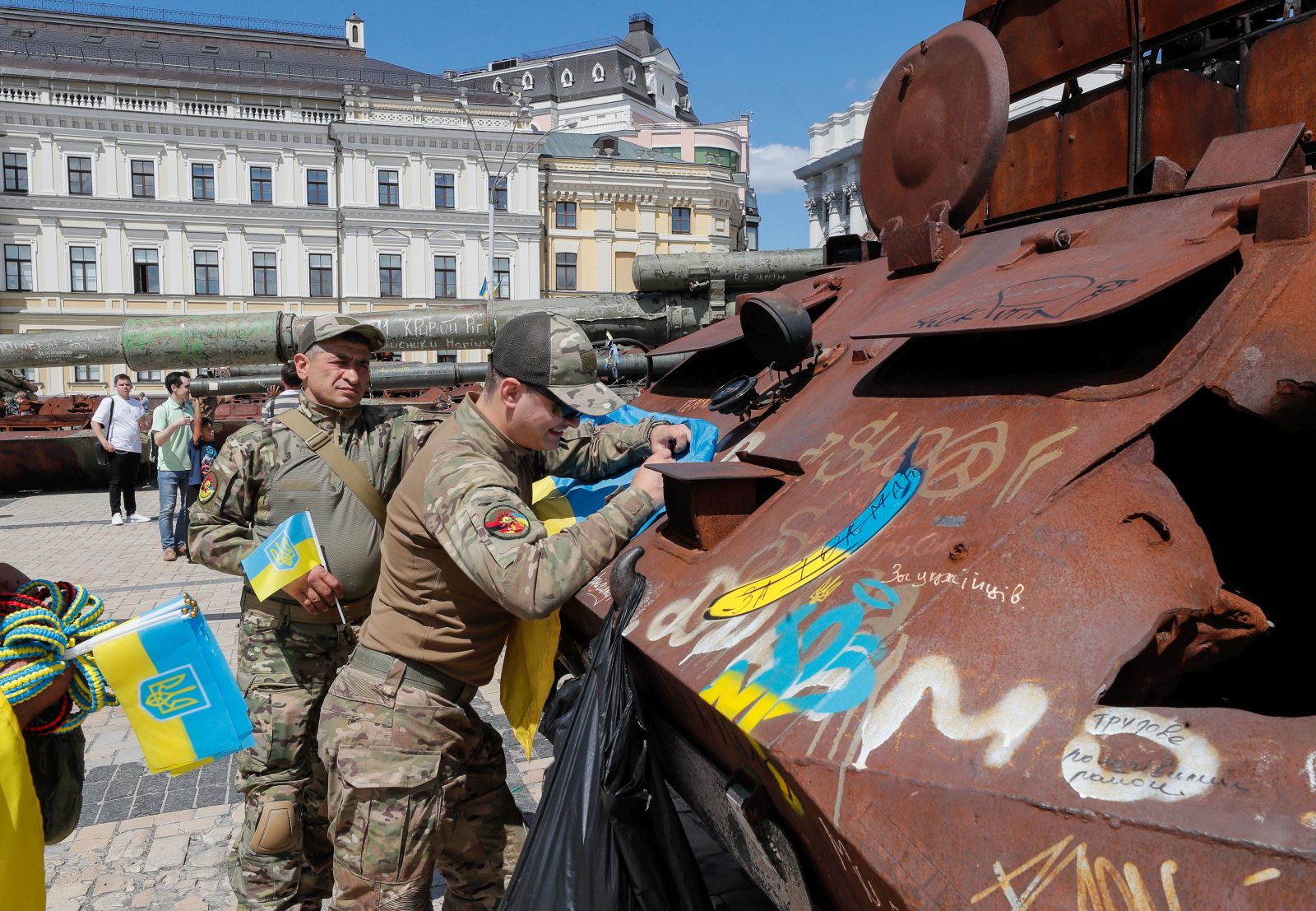epa10773848 Ukrainian servicemen sign a National flag as they visit an exhibition of destroyed Russian military machinery on display in front of St. Mikhailovsky Cathedral in Kyiv, Ukraine, 28 July 2023 Russian troops entered Ukrainian territory on 24 February 2022, starting a conflict that has provoked destruction and a humanitarian crisis.  EPA/SERGEY DOLZHENKO