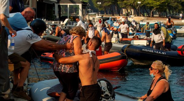 epa10772158 People evacuate by boats during a wildfire at Nea Anchialos, near Volos, Greece 27 July 2023. Explosions occurred at a munitions depot at Nea Anchialos base of the Hellenic Airforce near Volos in the afternoon of 27 July. According to authorities, the blast happened following a fire that had started in the Volos area and spread to the military airport, which functions as the base for the Tactical Air Force's 111 Combat Wing.  EPA/IKONOMOU VASSILIS