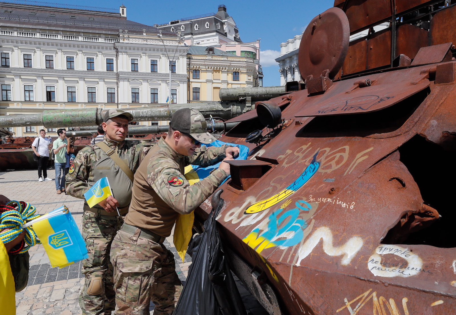 epa10773848 Ukrainian servicemen sign a National flag as they visit an exhibition of destroyed Russian military machinery on display in front of St. Mikhailovsky Cathedral in Kyiv, Ukraine, 28 July 2023 Russian troops entered Ukrainian territory on 24 February 2022, starting a conflict that has provoked destruction and a humanitarian crisis.  EPA/SERGEY DOLZHENKO