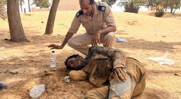 epa10777776 A Libyan border guard provides water to a Sub-Saharan African migrant, who reportedly have been abandoned by Tunisian authorities, upon his arrival in an uninhabited area on the Libya-Tunisia border near Al-Assah, 160 km west of Tripoli, Libya, 30 July 2023. Libyan border guards found more than 100 people, women, children and families, stranded in scorching summer temperatures and without water. According to the Red Crescent, Tunisian security forces have moved hundreds of migrants into the arid zone since June 2023.  EPA/STR