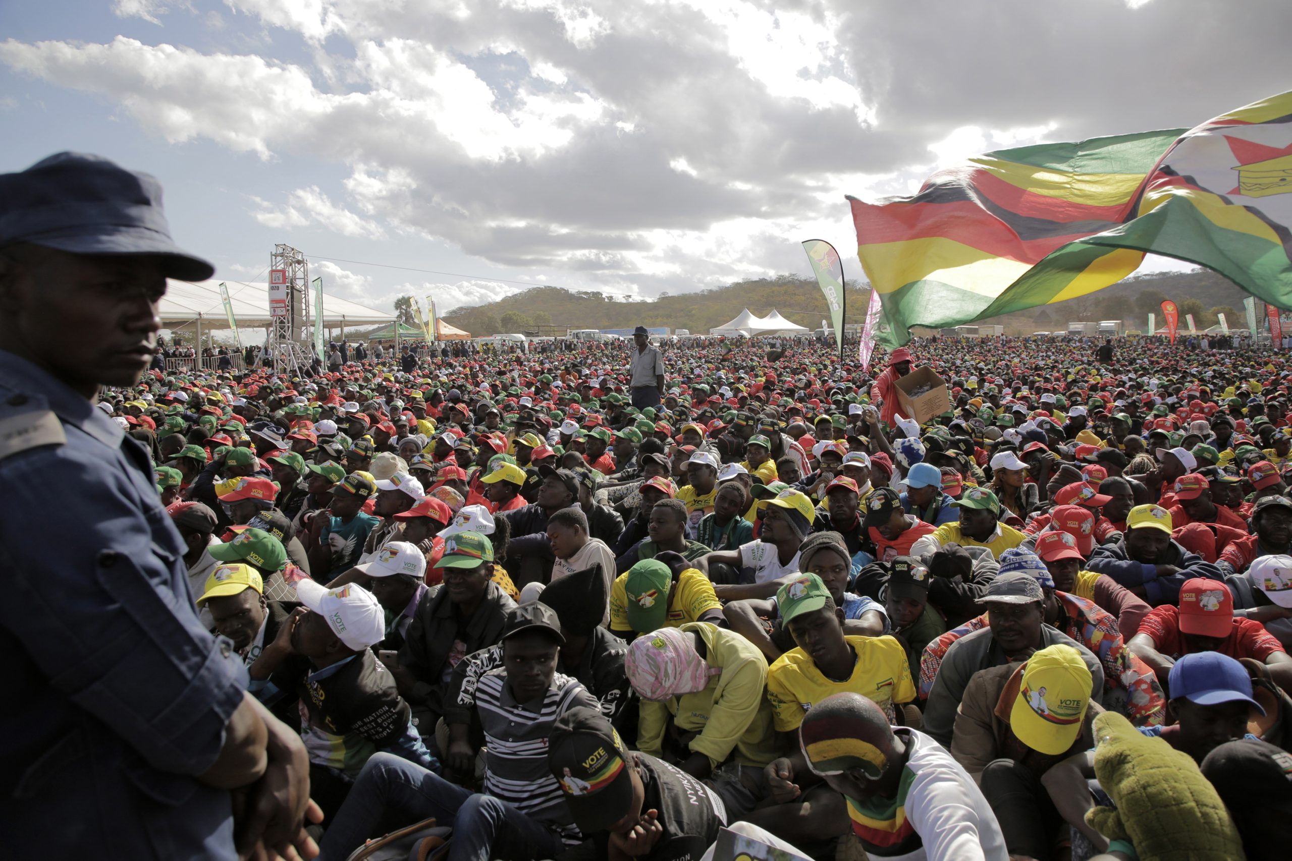 epa10786808 A police officer (L) watches supporters who attended an election campaign rally  addressed by President and party leader Emmerson Mmangagwa in Uzumba, Maramba, Zimbabwe, 05 August 2023. Zimbabweans go to the polls on 23 August 2023.  EPA/AARON UFUMELI