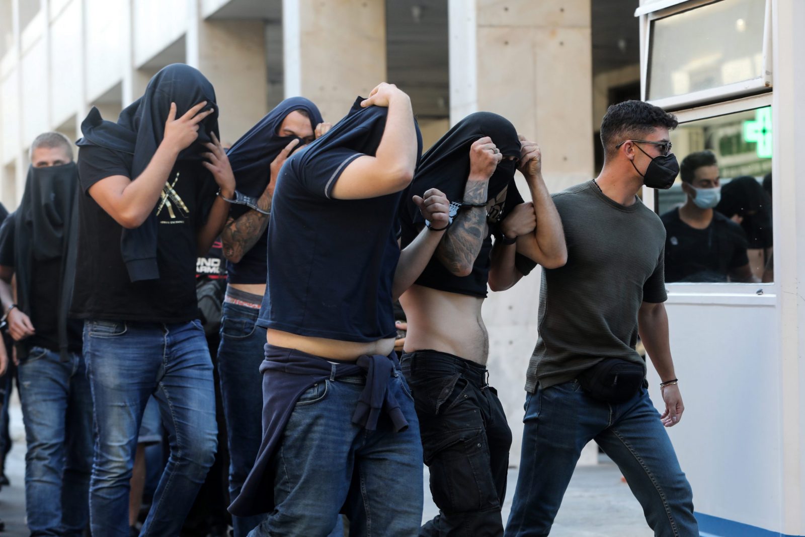 epa10791713 Hooligans, who were arrested after violent clashes between AEK and Dinamo Zagreb supporters in Athens, are transferred by police officers to appear before a public prosecutor, in Athens, Greece, 09 August 2023. Ninety four individuals, mostly Croatian nationals who were arrested during clashes between Greek and Croatian football fans in Athens on 07 August, will be presented before a prosecuting magistrate, while DNA samples are collected from all in order to identify the murderer of a 29-year-old AEK fan, who died during the clashes.  EPA/GEORGE VITSARAS