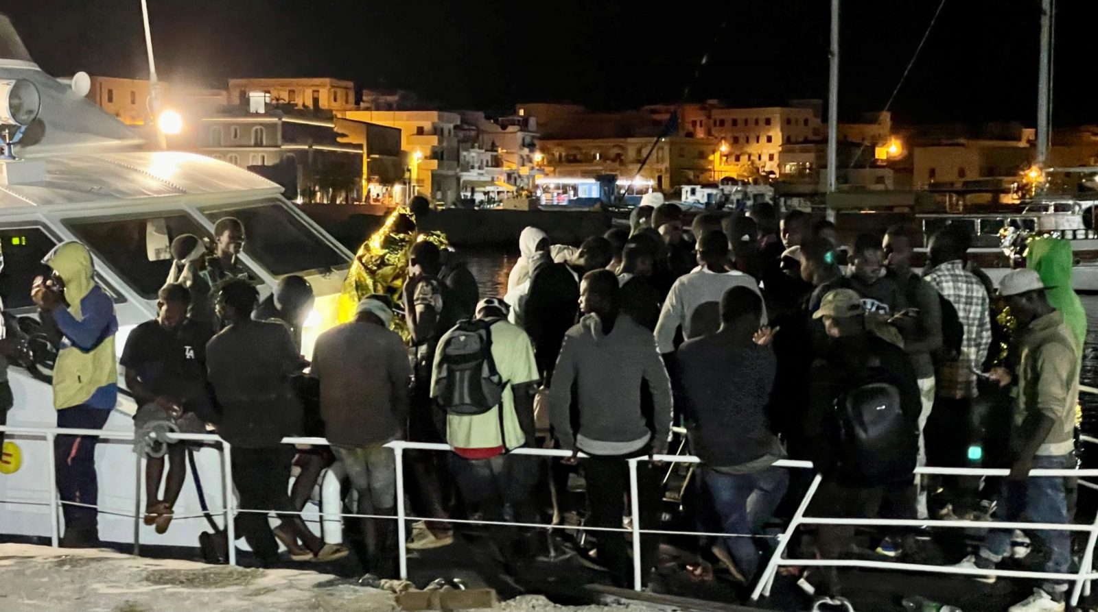 epa10792874 Migrants disembark from a harbor master's patrol boat that arrived at the commercial port of the island of Lampedusa, Italy, 10 August 2023. A group of 340 migrants were rescued at sea and taken to Lampedusa.  EPA/ELIO DESIDERIO
