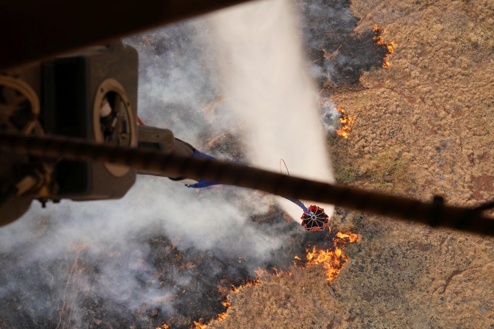 epa10793801 A handout photo made available by the US Army National Guard on 10 August 2023 shows a Hawaii Army National Guard CH47 Chinook dropping water on a burning wildfire on the Island of Maui, Hawaii, USA, 09 August 2023 (issued 10 August 2023). The White House on 10 August declared the ongoing Hawaii wildfires a major disaster, after hundreds of buildings on the island were destroyed, thousands of people were evacuated and at least 36 people lost their lives.  EPA/MASTER SGT ANDREW JACKSON / US ARMY NATIONAL GUARD HANDOUT NO SALES, EDITORIAL USE ONLY HANDOUT EDITORIAL USE ONLY/NO SALES