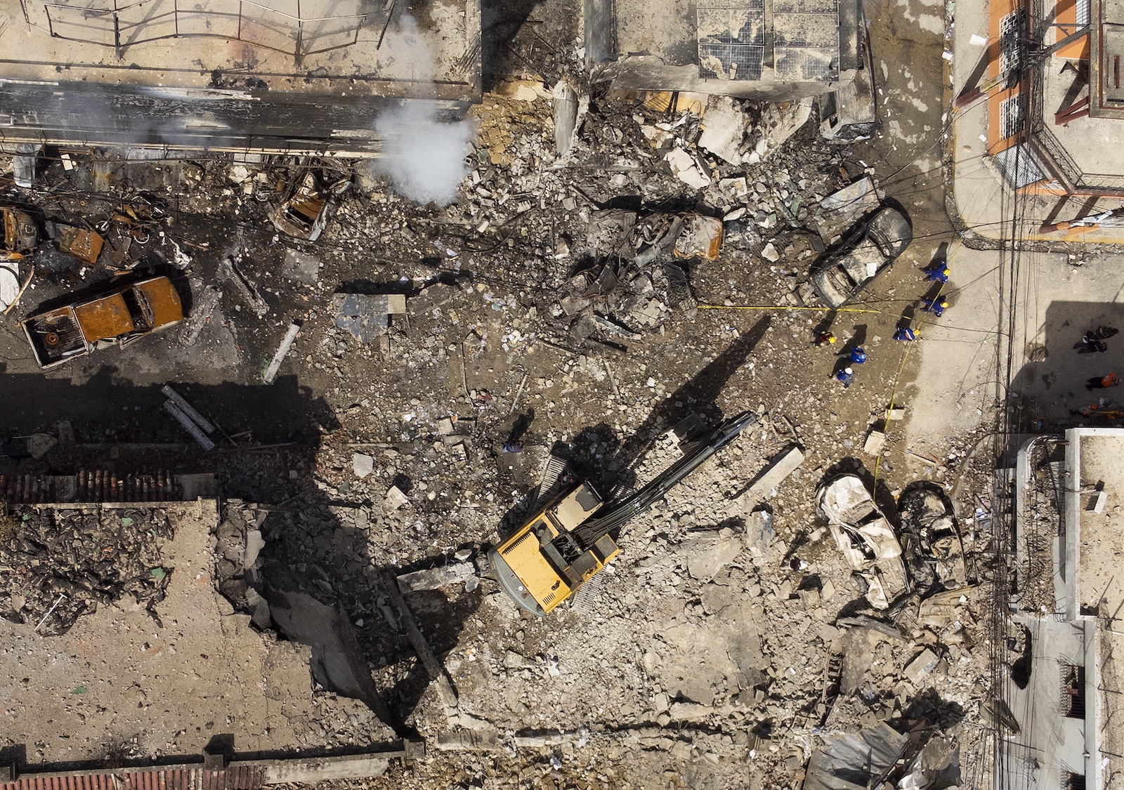 epa10801701 A photo taken with a drone shows rescue workers searching for missing persons among the rubble the day after an explosion occurred in San Cristobal, Dominican Republic, 15 August 2023. At least 10 people were killed after the blast of unknow origin caused a fire and the damage to vehicles and buildings on 14 August.  EPA/Orlando Barria