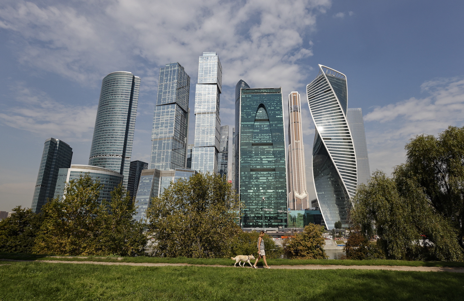 epa10805245 A woman walks a dog in front of the Moscow-City business center and Expocentre exhibition center, where a drone reportedly fell in Moscow, Russia, 18 August 2023. According to the Russian Ministry of Defense, air defense systems on 18 August shot a drone causing a change of its flight trajectory before falling on a non-residential building near Krasnopresnenskaya Embankment in Moscow. The Russian Defense Ministry blamed Ukraine for the attack that left no casualties. Moscow Mayor Sergei Sobyanin said the drone fell in the Expocentre zone and no significant damage was caused to the building.  EPA/SERGEI ILNITSKY