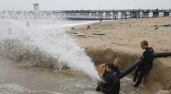 epa10811121 People play with a drainage hose on the beach in Seal Beach, California, USA, 20 August 2023. Southern California is under a tropical storm warning for the first time in history as Hilary makes landfall. The last time a tropical storm made landfall in Southern California was 15 September 1939, according to the National Weather Service.  EPA/CAROLINE BREHMAN