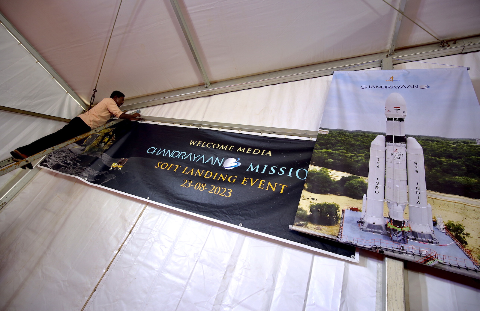 epa10815351 Indian labourers hang a poster during the soft landing of the 'Chandrayaan-3 Mission' event at ISRO Telemetry, Tracking and Command Network (ISTRAC) in Bangalore, India, 23 August 2023. Indian Space Research Organisation (ISRO) space exploration Chandrayaan-3 Mission is expected to land on the moon on 23 August at approximately 18:04 (IST).  EPA/JAGADEESH NV