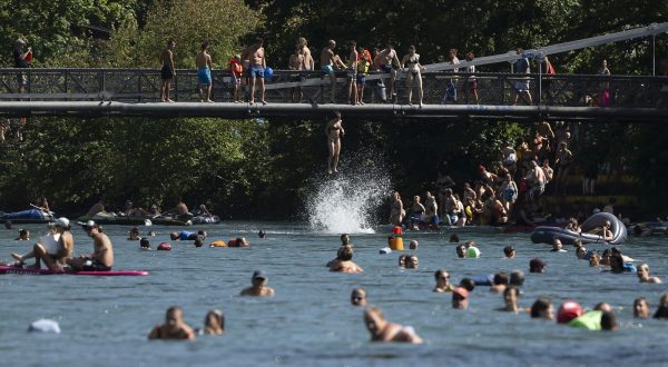 epa10810771 A woman jump from Schonausteg bridge in the Aare River during the sunny and warm weather in Bern, Switzerland, 20 August 2023. Many parts of Switzerland have been experiencing a period of extreme heat. A heat dome has been hovering over the country for an indefinite period since 18 August.  EPA/ANTHONY ANEX