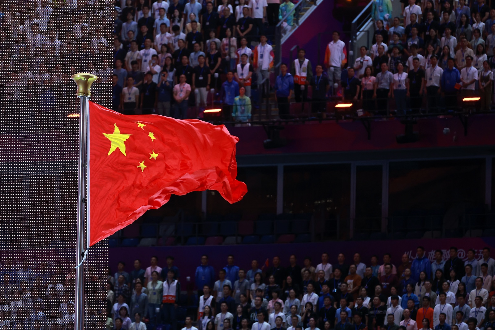 epa10878387 People attend the flag raising ceremony during the opening ceremony of the 19th Asian Games Hangzhou 2022 at the Olympic Sports Centre Stadium in Hangzhou, China, 23 September 2023. The 2022 Asian Games were postponed due to the Covid-19 pandemic and are held between 23 September and 08 October 2023.  EPA/ALEX PLAVEVSKI