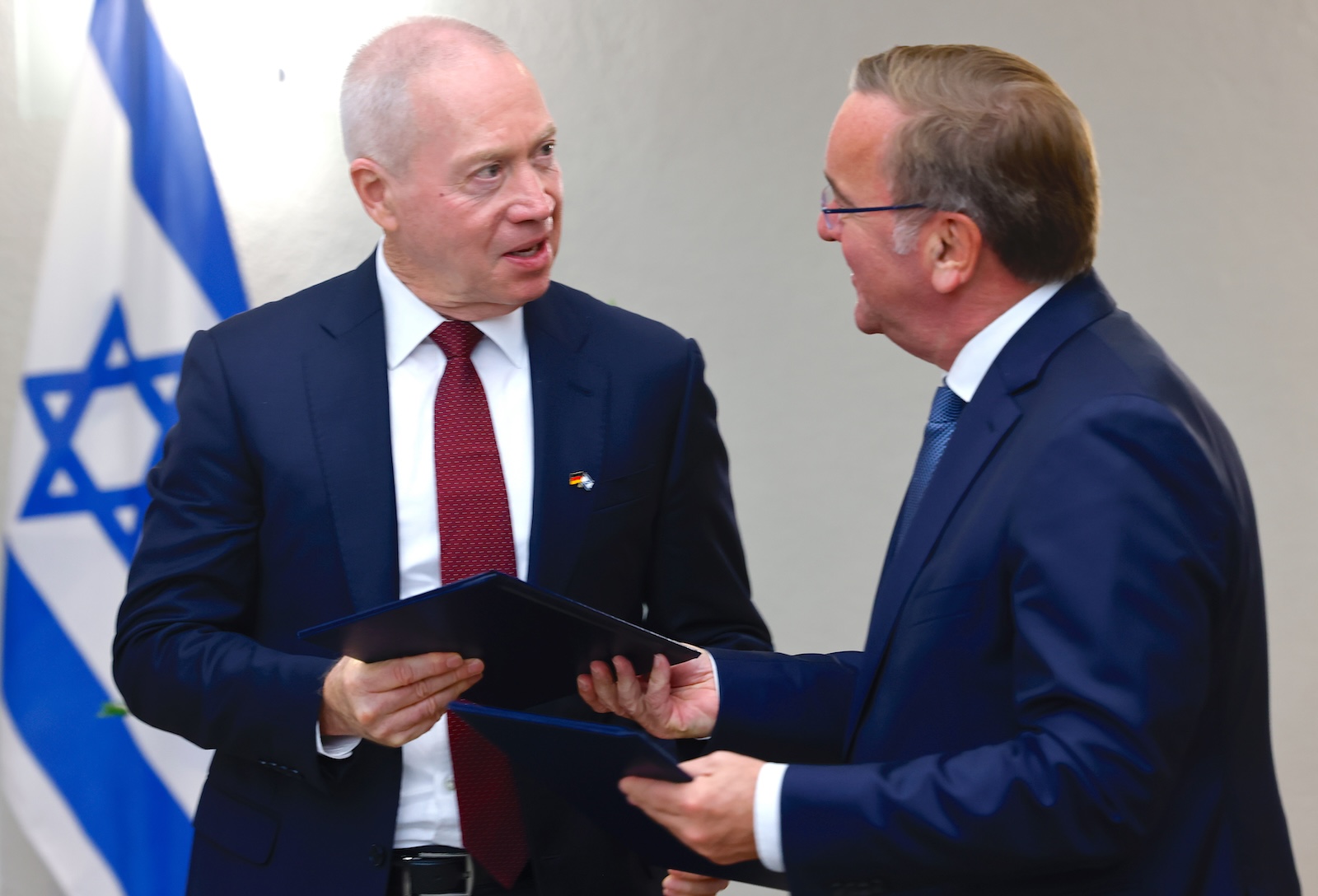 epa10887468 Israeli Minister of Defense Yoav Gallant (L) and German Defense Minister Boris Pistorius exchange papers after signing an agreement on the purchase of the Israeli Arrow 3 missile defense system, in Berlin, Germany, 28 September 2023. The Arrow 3 system is intended to offer Germany and its neighbors better protection against possible missile attacks. The guided missiles are designed to destroy long-range enemy missiles outside the Earth's atmosphere by a direct hit. The cost, according to Israeli figures, is nearly four billion euros. It is the largest arms deal in Israeli history.  EPA/HANNIBAL HANSCHKE