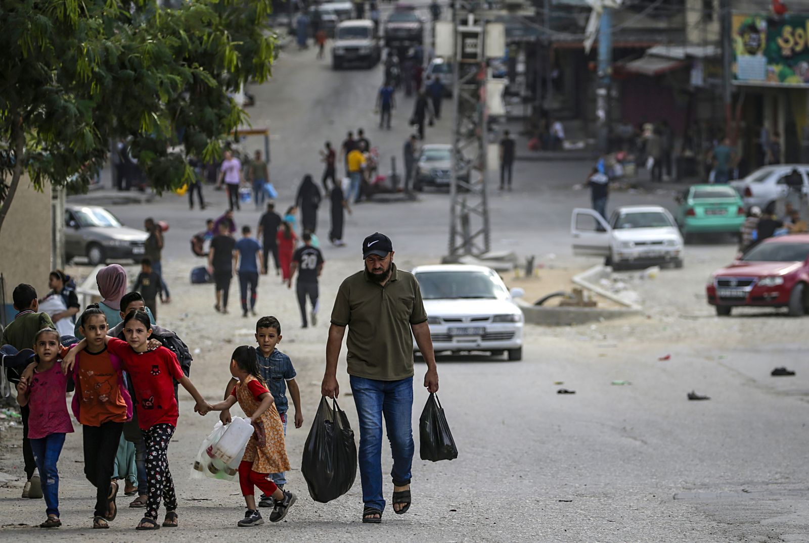 epa10922364 A Palestinian carrying food walks with his children in Al Shejaeiya neighbourhood, east of Gaza City, 16 October 2023. Israel has warned all citizens of the Gaza Strip to move to the south ahead of an expected invasion. More than 2,750 Palestinians and 1,400 Israelis have been killed according to the Israel Defense Forces (IDF) and Palestinian Health Ministry after Hamas militants launched an attack against Israel from the Gaza Strip on 07 October.  EPA/MOHAMMED SABER