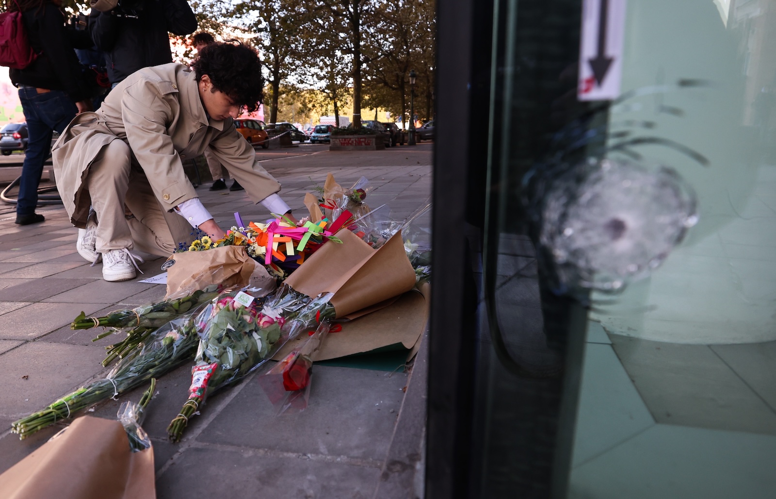 epa10923641 Flowers are put in place at the bank branch, where two football supporters from Sweden were shot dead in a terror attack in Brussels, Belgium, 17 October 2023. A man, suspected of killing two Swedish football supporters on 16 October, was shot by the Police during an operation and has died, Belgian Police said. Following the incident, the Brussels Capital Region has increased its terror threat to level 4, the highest, the National Crisis Center announced.  EPA/OLIVIER HOSLET